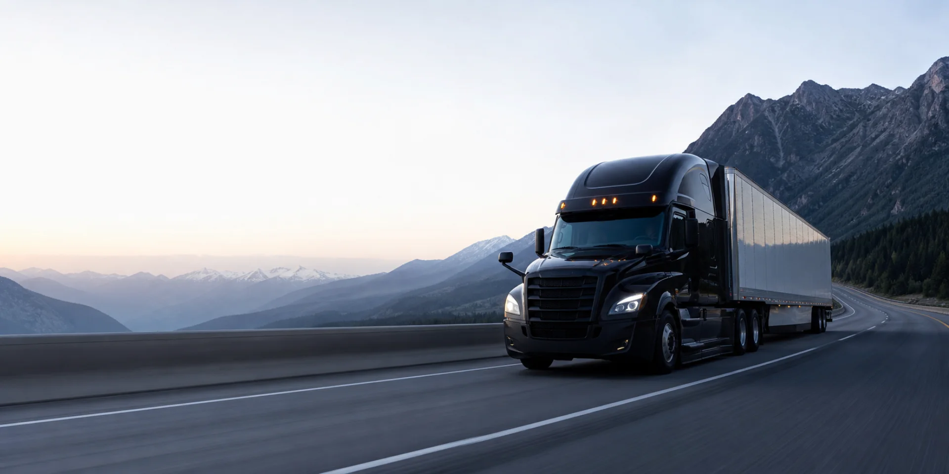 Black tractor-trailer traveling on a mountain highway